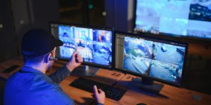 Male security guard monitoring modern CCTV cameras indoors.